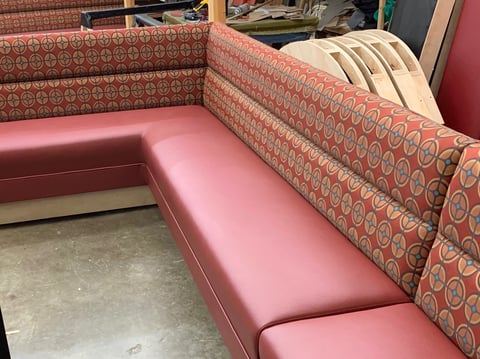 Pink and coral upholstered sectional sofa with geometric pattern in a showroom or workshop setting