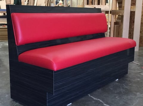 Red and black upholstered banquette bench with pink cushioned seating and back support, displayed indoors.