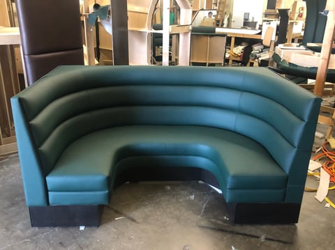 Curved teal-blue booth seating with black base displayed in furniture showroom