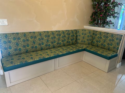 L-shaped kitchen bench seat with blue and gold floral cushions and white wood base in a tiled room