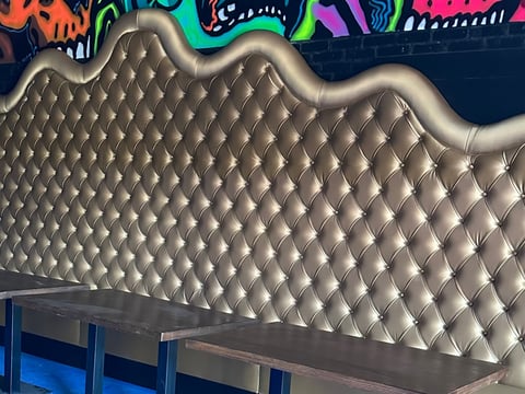Silver quilted headboard wall with wavy edges and colorful graffiti art above it