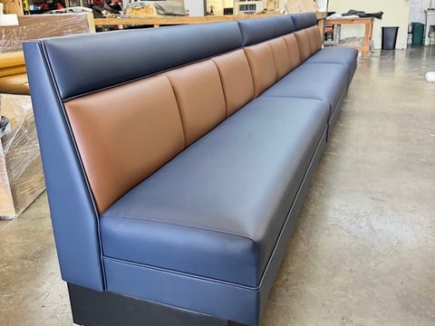 Modern booth seating with blue and tan leather cushioning in warehouse or showroom setting